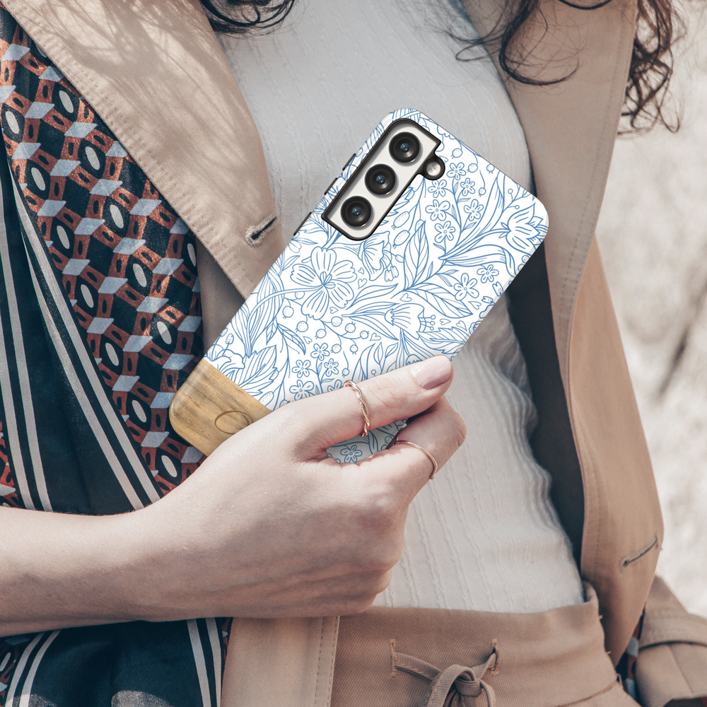 Elegant Samsung Galaxy phone case featuring a blue floral line art design with a woodgrain-textured bottom, personalized with a name engraving. Available for Samsung Galaxy S25 Ultra, S24 FE, S23, and more.