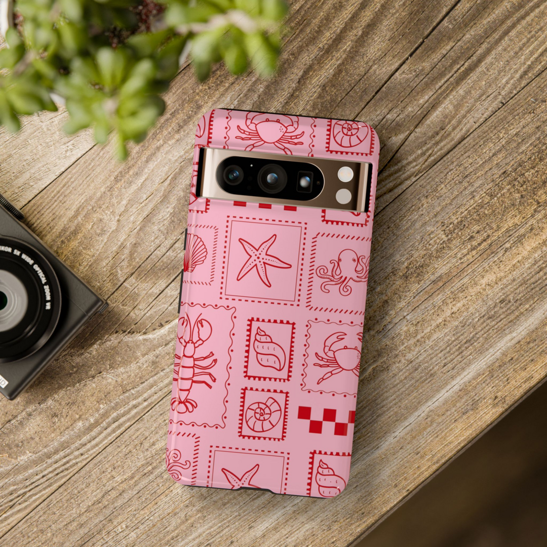 Pink Google Pixel case with red sea creature stamps including lobster, shell, starfish, crab, and octopus in a playful coastal grid pattern


