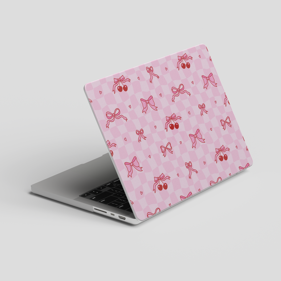 Cute pink MacBook case with red bows, cherries, and hearts on a gingham checker pattern, ideal for students, creatives, and girly office style.