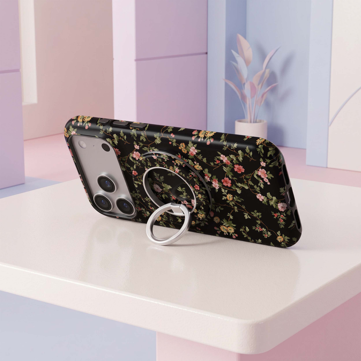 CASELIX Midnight Florals MagSafe Ring Holder featuring delicate pink and golden-yellow wildflowers with green leafy vines on a classic black background.
