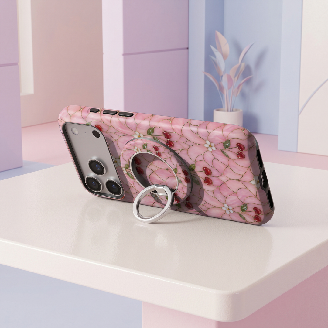 Cherry Blossom Glass MagSafe ring holder featuring red cherries, delicate white flowers and green leaves on a pink stained glass background with a silver magnetic phone grip.