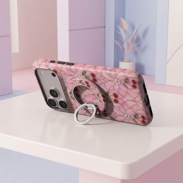 Cherry Blossom Glass MagSafe ring holder featuring red cherries, delicate white flowers and green leaves on a pink stained glass background with a silver magnetic phone grip.