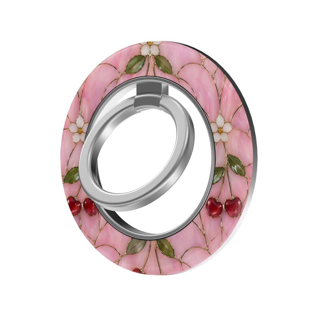 Cherry Blossom Glass MagSafe ring holder featuring red cherries, delicate white flowers and green leaves on a pink stained glass background with a silver magnetic phone grip.