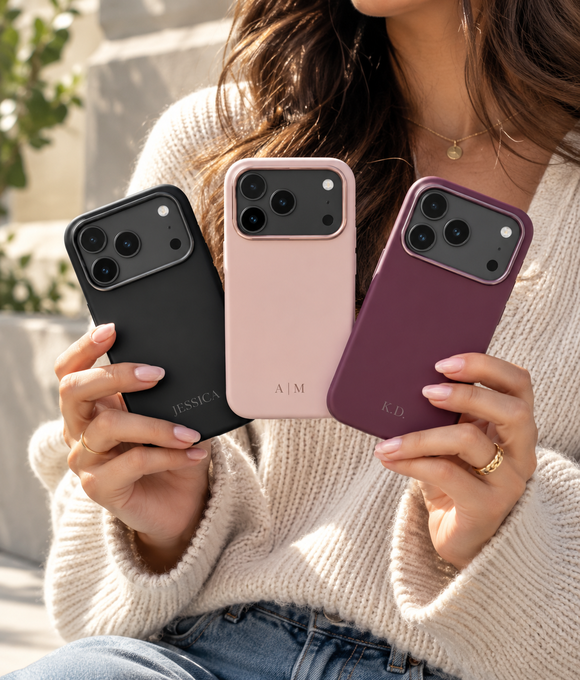 Woman holding personalized MagSafe silicone phone cases in Black, Blush Pink and Plum outdoors.