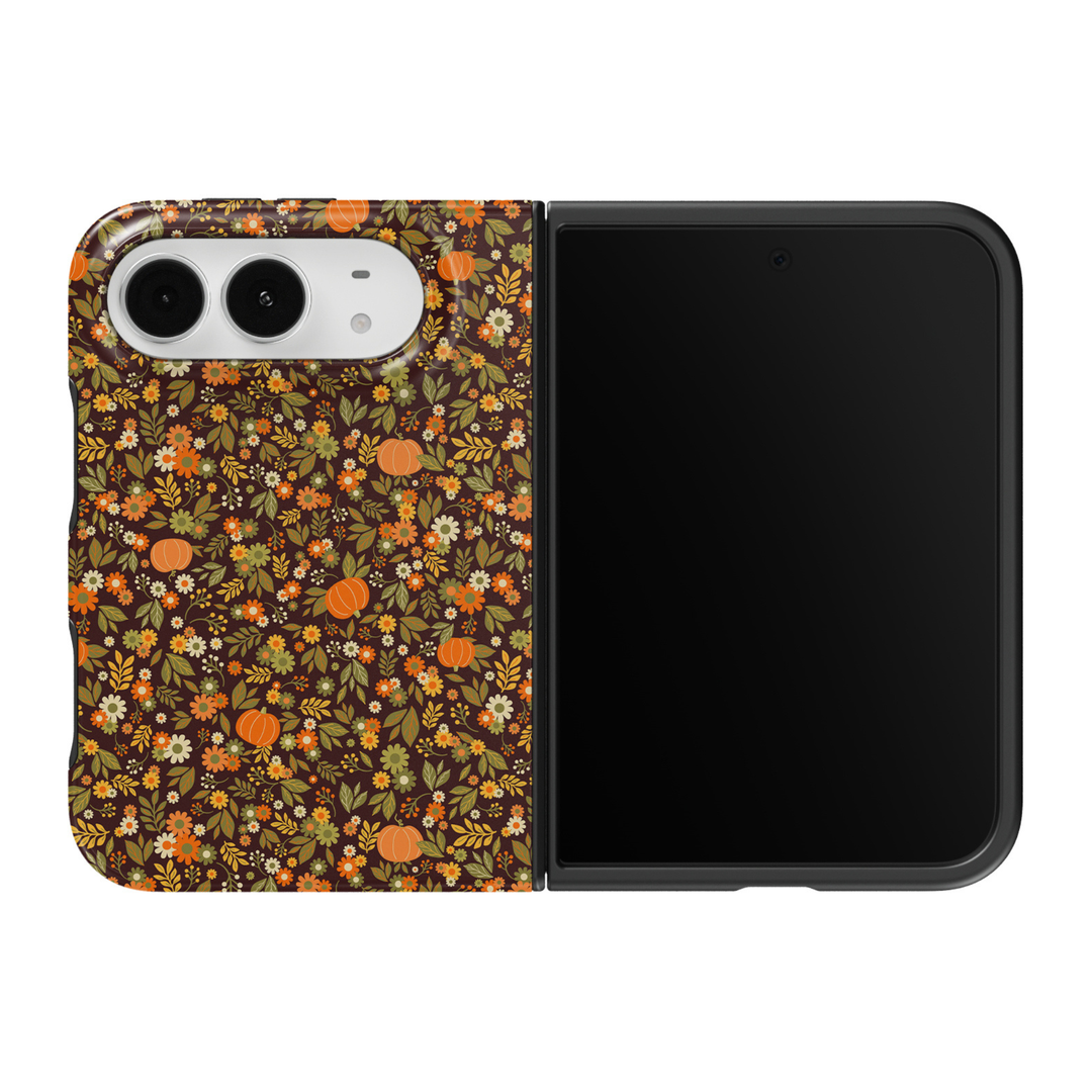 CASELIX Pumpkin Meadow iPhone Duo Tough MagSafe folding phone case featuring a dark chocolate brown background with tiny orange pumpkins, retro orange and cream daisies, mustard yellow wildflowers, sage green leaves, and delicate autumn botanical details. Cute fall floral phone case for women with a glossy printed finish, vintage 70s-inspired cottagecore aesthetic, cozy pumpkin patch style, and protective two-piece foldable design.