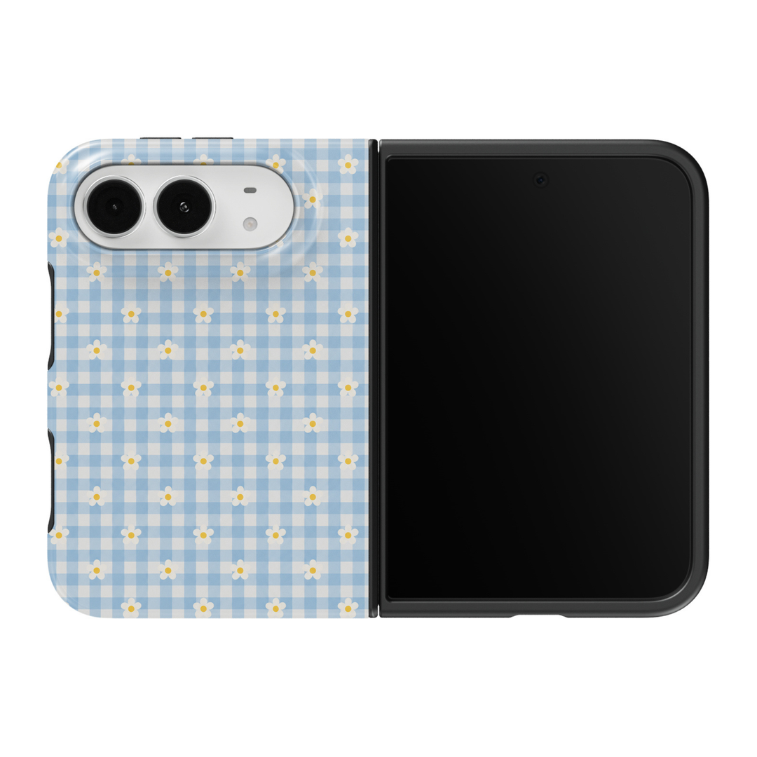 CASELIX Daisy Gingham iPhone Duo Tough MagSafe folding phone case featuring a pastel baby-blue and ivory-white gingham checkered background decorated with evenly spaced white daisy flowers and sunny yellow centers. Cute blue gingham floral phone case for women with a glossy printed finish, feminine cottagecore aesthetic, vintage picnic-inspired checkered pattern, preppy spring and summer fashion style, minimalist daisy artwork, and protective two-piece foldable construction.