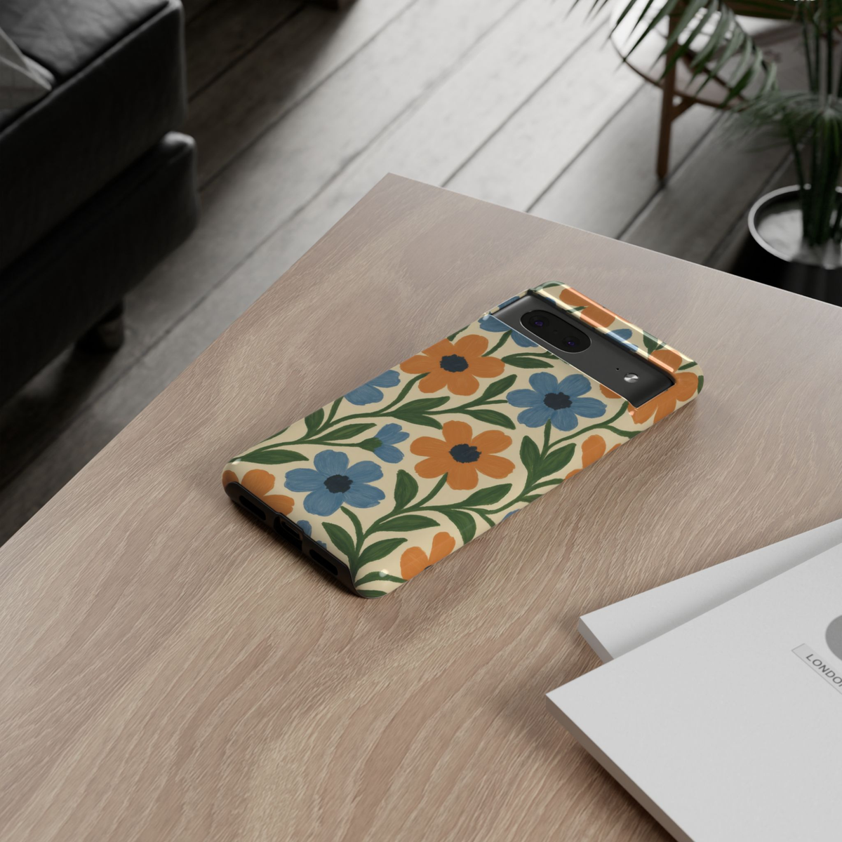 Google Pixel 10 protective phone case featuring a retro Scandinavian floral pattern with hand-painted blue and orange flowers, green leaves, and a soft cream background.