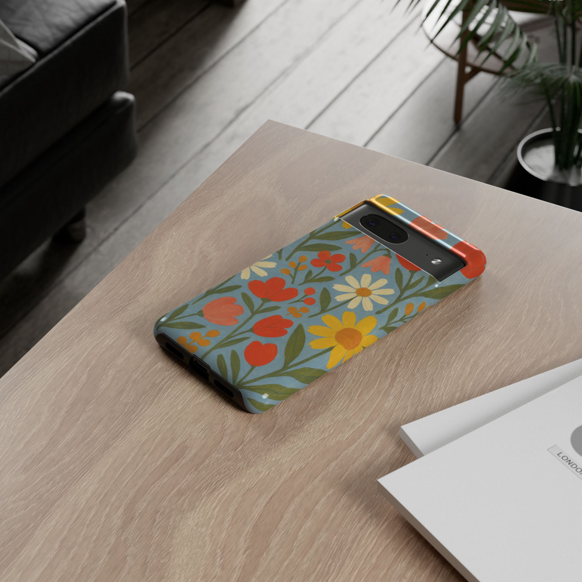 Google Pixel 10 protective phone case featuring a hand-painted Scandinavian wildflower pattern with daisies, tulips, and colorful floral illustrations on a soft blue background.