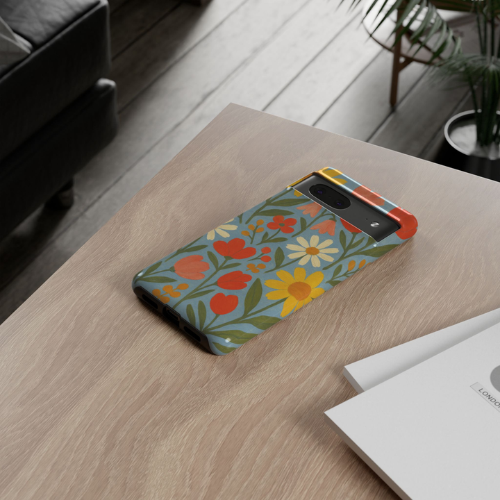 Google Pixel 10 protective phone case featuring a hand-painted Scandinavian wildflower pattern with daisies, tulips, and colorful floral illustrations on a soft blue background.