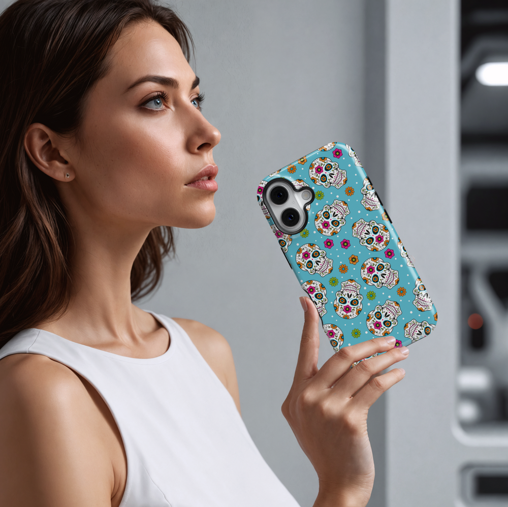 Bright sugar skull iPhone case with vibrant orange, pink, green, and blue floral patterns on a turquoise blue background. Features traditional Day of the Dead (Día de los Muertos) skull art for iPhone 16 Pro Max, 15, 14, and 13 models. Bold, festive, and eye-catching design perfect for Halloween and fall celebrations.


