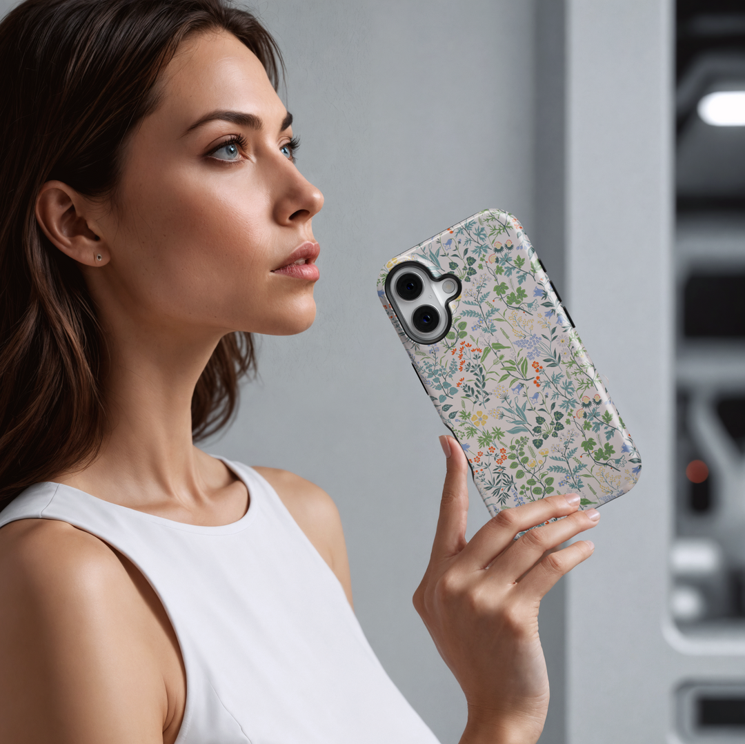 iPhone case featuring a delicate and colorful wildflower pattern with tiny blossoms and greenery on a soft cream background.