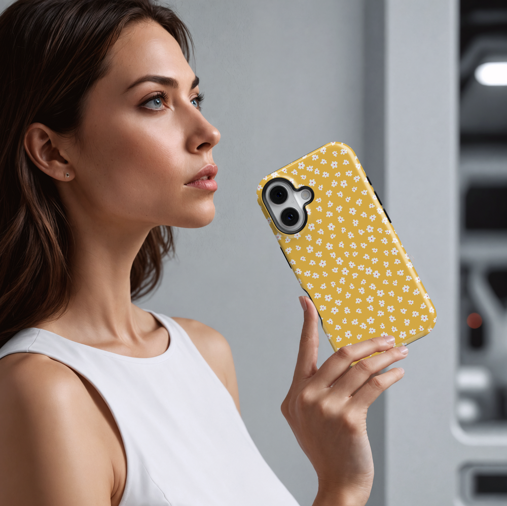 iPhone case featuring a playful mustard yellow background with a scattered pattern of tiny white and pink daisies.