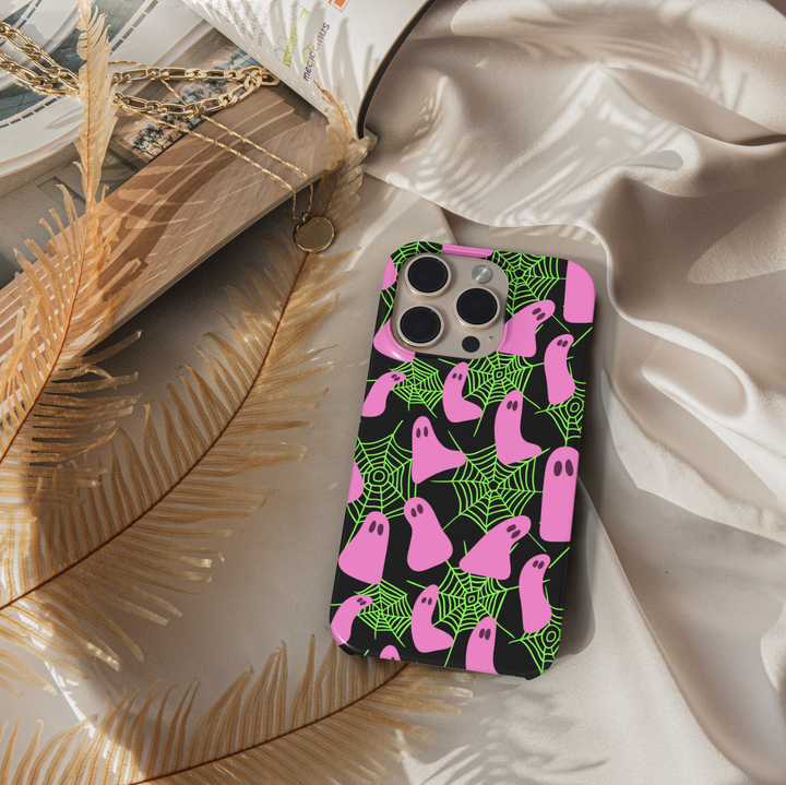 Neon Halloween iPhone case with pink ghosts and green spider webs on a black background. Cute spooky aesthetic protective phone cover for iPhone 15, iPhone 14, iPhone 13 Pro Max, and more. Fun girly ghost phone case perfect for Halloween season.