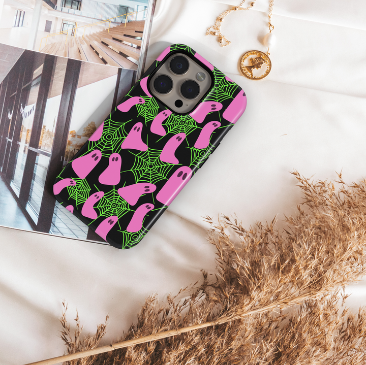Neon Halloween iPhone case with pink ghosts and green spider webs on a black background. Cute spooky aesthetic protective phone cover for iPhone 15, iPhone 14, iPhone 13 Pro Max, and more. Fun girly ghost phone case perfect for Halloween season.
