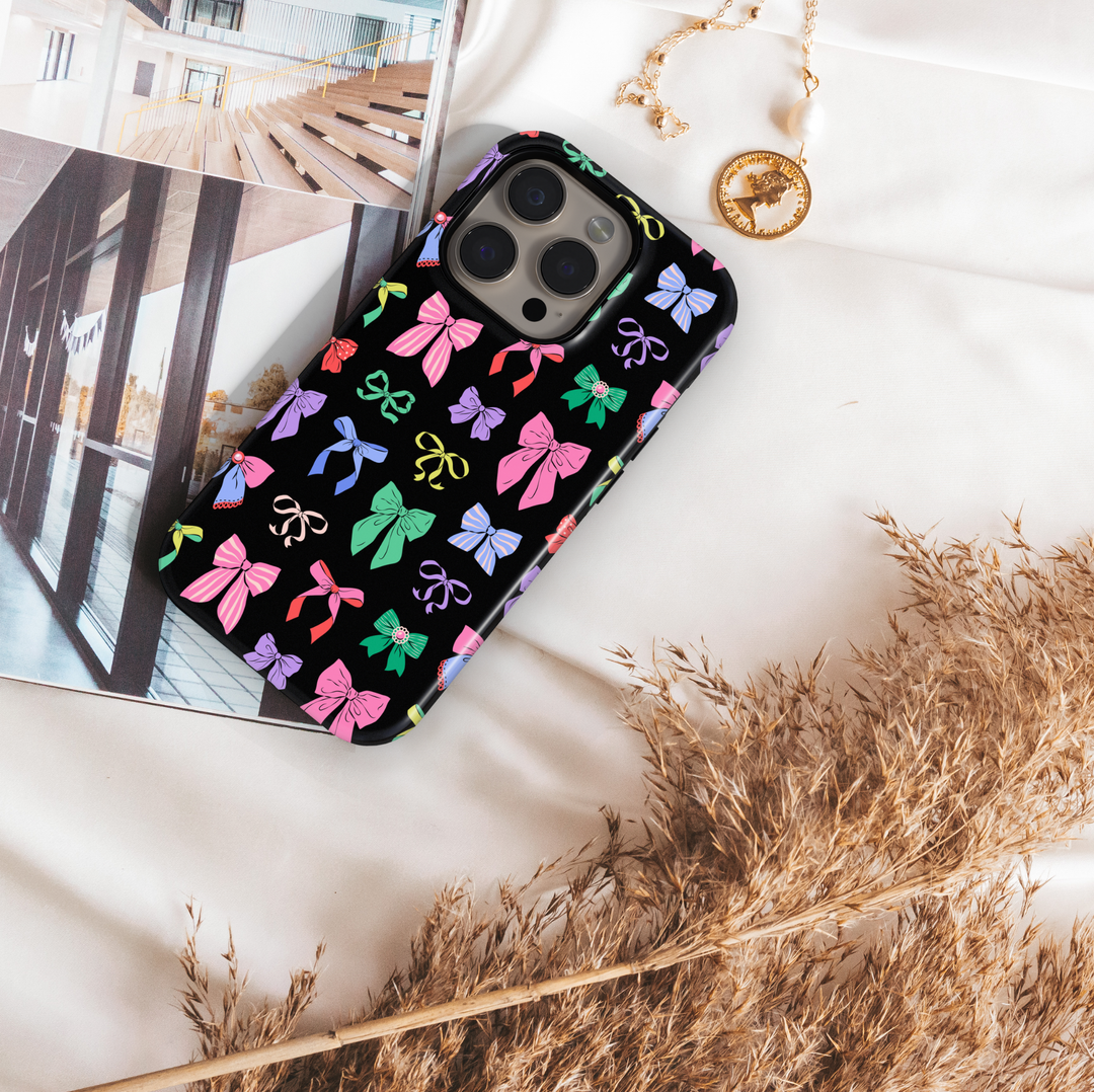 Black phone case with colorful bow pattern, coquette aesthetic girly ribbon design for iPhone and Samsung