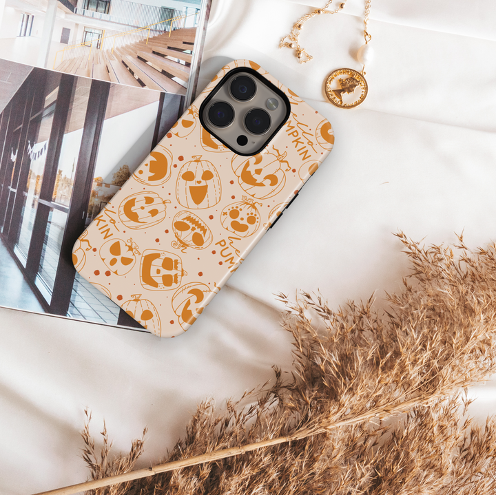 Pumpkin doodle Halloween phone case with orange jack-o’-lantern designs on a neutral background for iPhone and Samsung.