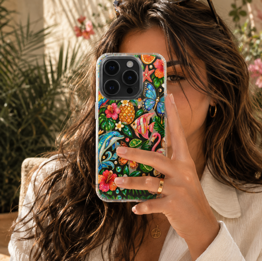 Clear MagSafe iPhone case with colorful tropical flowers, flamingo, dolphin, butterflies, pineapple, fish and jeweled island-inspired details.