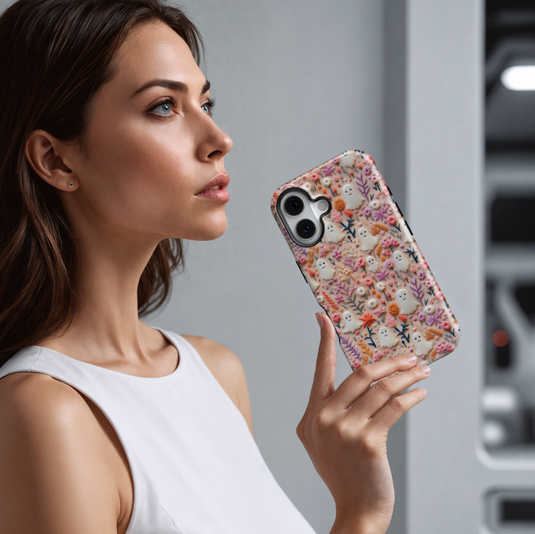 Cute Halloween ghost iPhone case with pastel pink, peach, and orange flowers on a soft background. Perfect spooky season aesthetic with smiling mini ghosts.