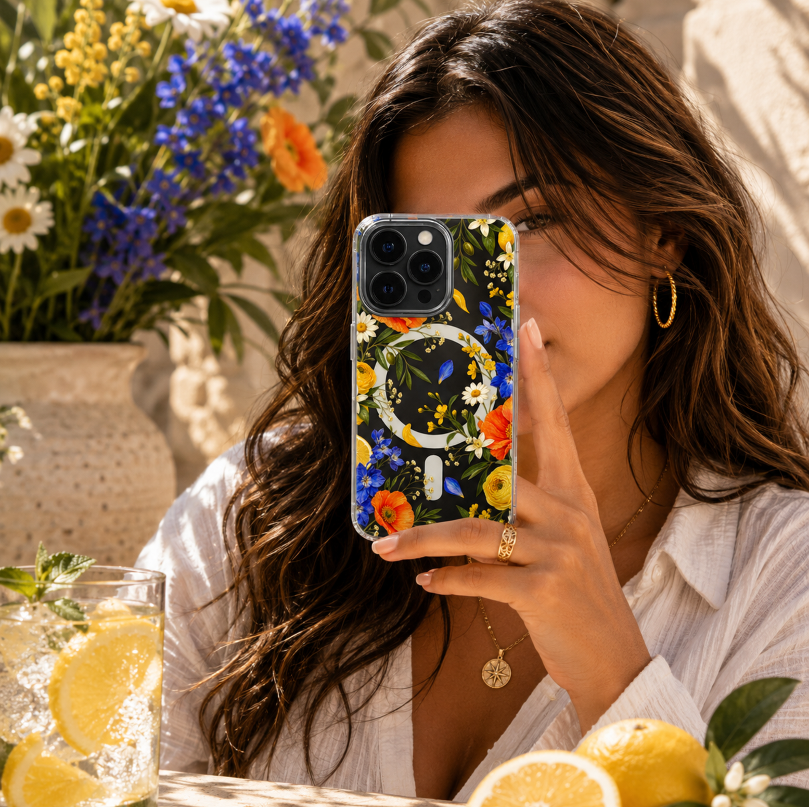 Clear MagSafe iPhone case with vibrant orange poppies, yellow flowers, blue wildflowers, citrus and green botanical leaves.