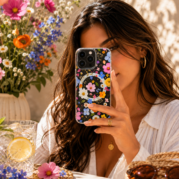 Clear MagSafe iPhone case with colorful pink, blue, orange, yellow and white wildflowers in a vibrant botanical pattern.