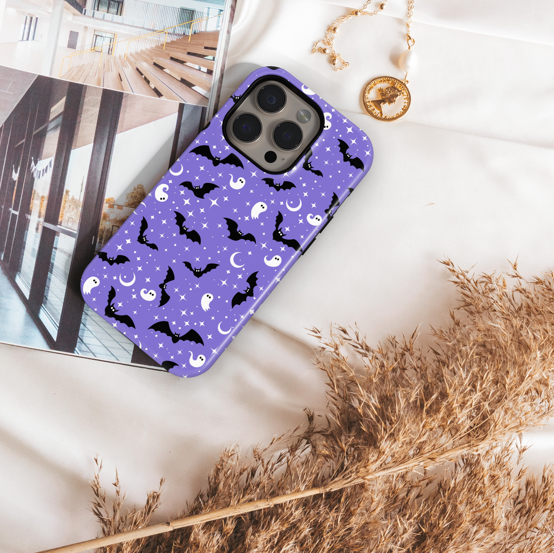 Purple tough phone case with cute white ghosts, black bats, moons, and stars – Halloween aesthetic protective iPhone and Samsung cover.