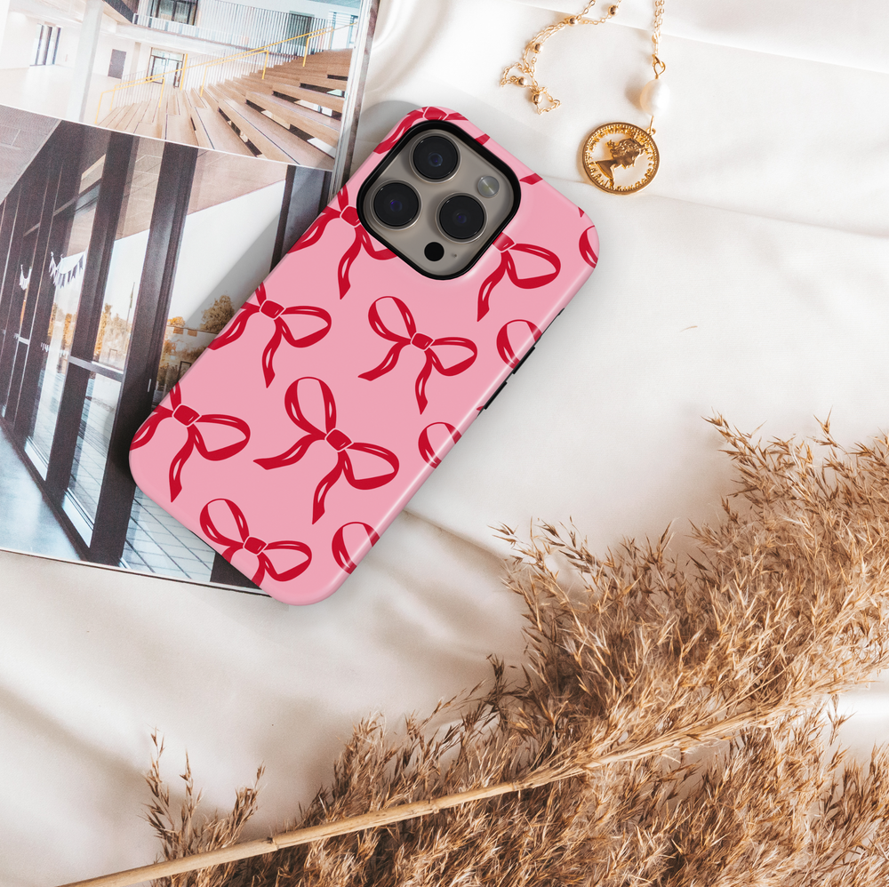 Pink phone case with red bow pattern, girly coquette aesthetic design, glossy ribbon print protective phone cover for iPhone and Samsung