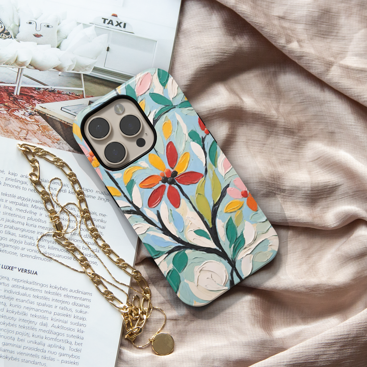Painterly floral iPhone case featuring textured oil painting flowers in red, yellow, green, and blue with expressive brushstrokes.