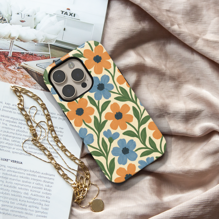 Vintage floral iPhone case featuring blue and orange hand-painted flowers with green leaves on a cream background.