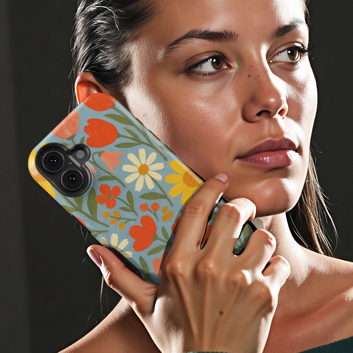Retro floral iPhone case featuring colorful daisies, tulips, and wildflowers on a soft blue background with vintage folk art styling.