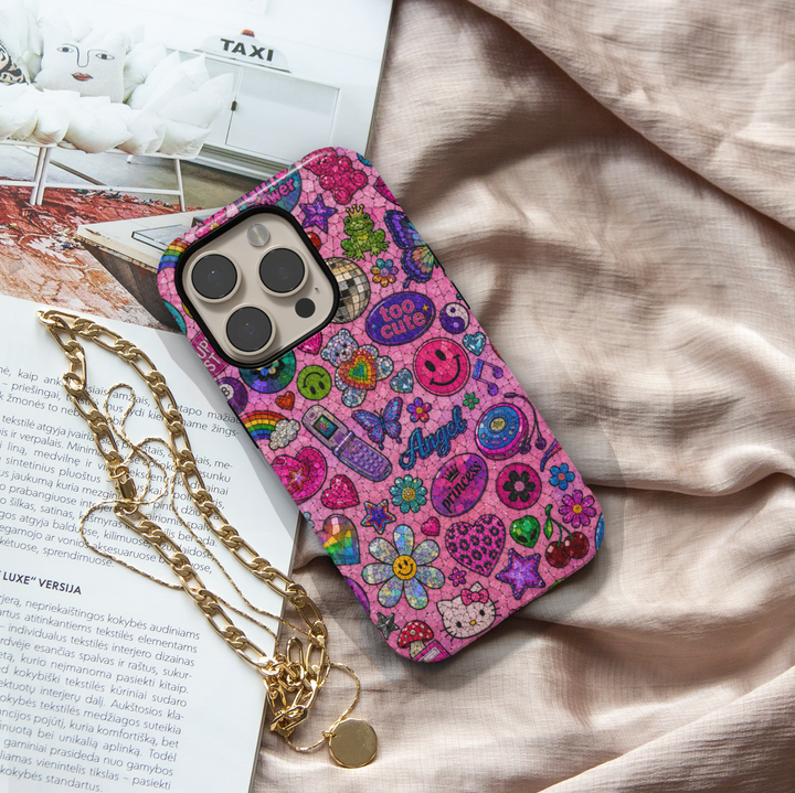 Cute pink Y2K iPhone case featuring colorful sticker icons, butterflies, smiley faces, hearts, cherries, flowers, and retro aesthetic artwork.