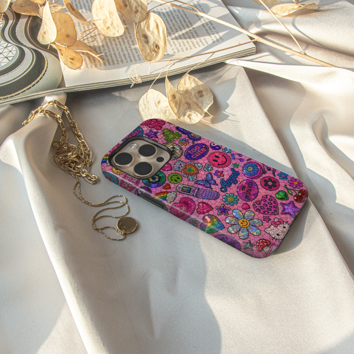 Cute pink Y2K iPhone case featuring colorful sticker icons, butterflies, smiley faces, hearts, cherries, flowers, and retro aesthetic artwork.
