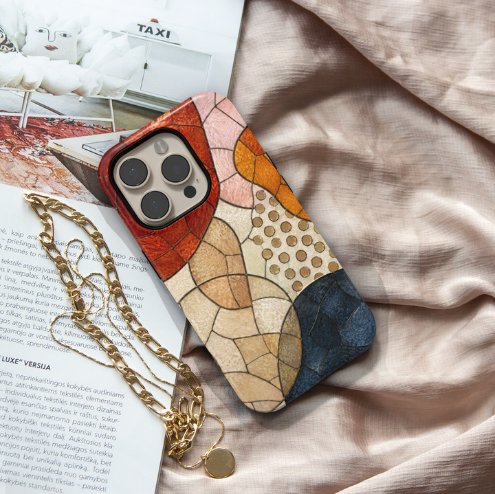 Modern abstract iPhone case featuring neutral geometric mosaic shapes in terracotta, cream, caramel, and navy tones.