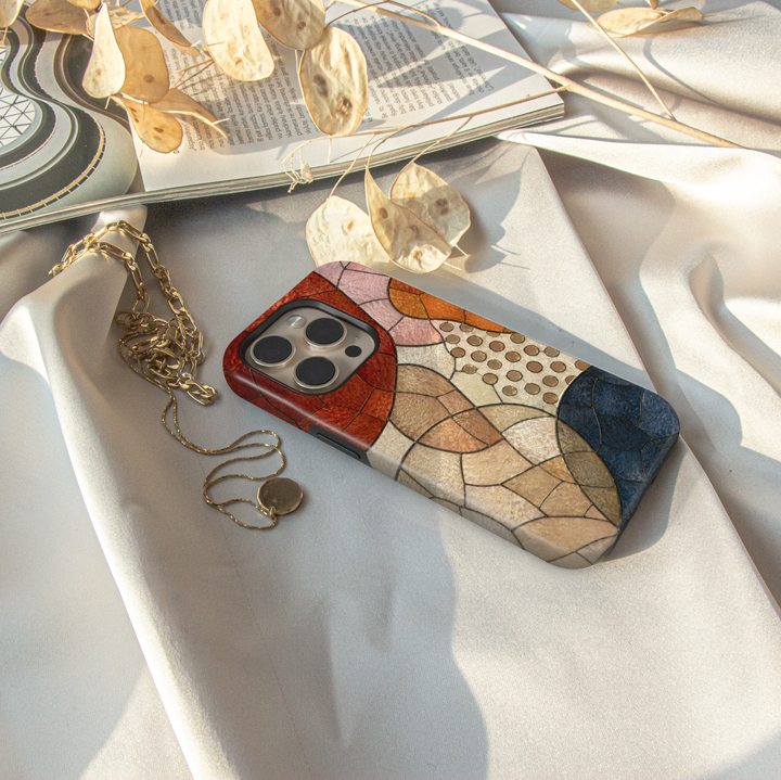 Modern abstract iPhone case featuring neutral geometric mosaic shapes in terracotta, cream, caramel, and navy tones.