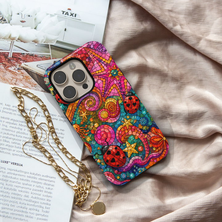 Colorful stained glass iPhone case featuring ladybugs, swirling patterns, stars, and whimsical mosaic artwork.