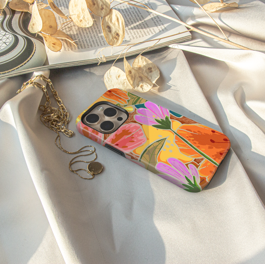 Colorful floral iPhone case featuring oversized wildflowers, botanical leaves, and vibrant retro-inspired floral artwork.