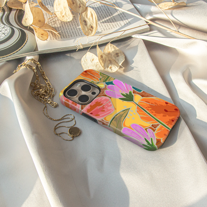 Colorful floral iPhone case featuring oversized wildflowers, botanical leaves, and vibrant retro-inspired floral artwork.
