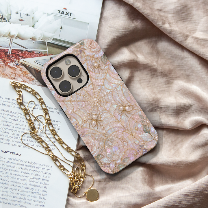 Elegant iPhone case featuring blush pink pearl spider webs, jeweled spiders, iridescent gemstones, florals, and luxurious gothic artwork.