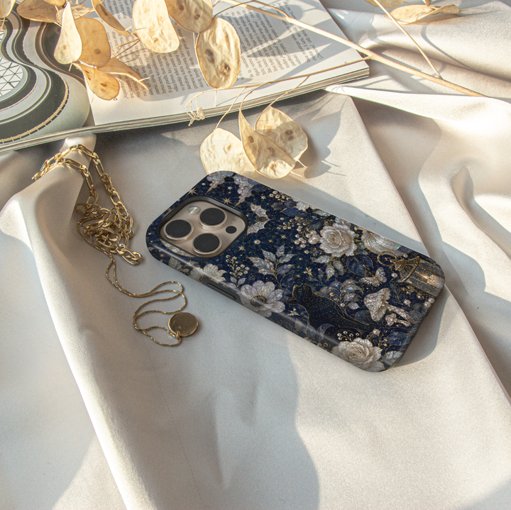 Elegant black cat iPhone case featuring moonlit flowers, pearl pumpkins, glowing lantern, mushrooms, butterflies, and celestial night sky artwork.