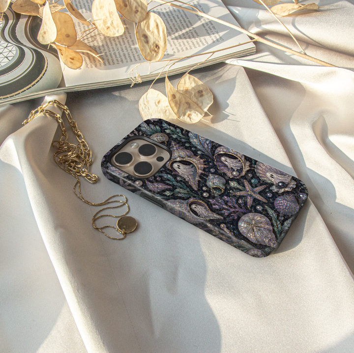 Midnight coastal Halloween iPhone case featuring pearl ghosts inside seashells with starfish, coral, sea glass, pearls, and iridescent ocean details.