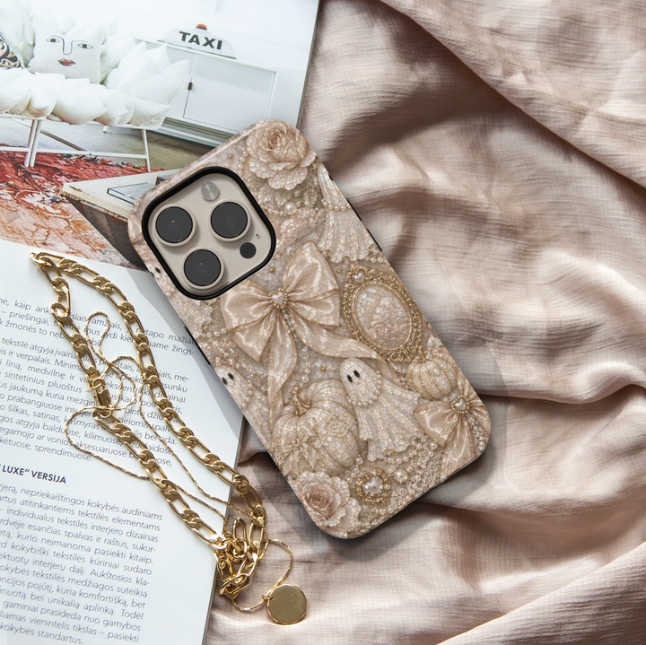 Elegant Ghost Coquette iPhone case featuring pearl ghost, satin bows, ivory pumpkins, vintage mirror, pearls, lace, and neutral Halloween décor.