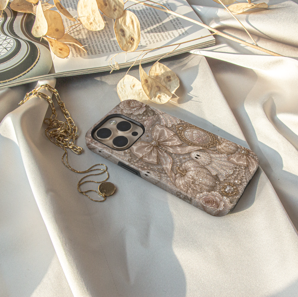 Elegant Ghost Coquette iPhone case featuring pearl ghost, satin bows, ivory pumpkins, vintage mirror, pearls, lace, and neutral Halloween décor.