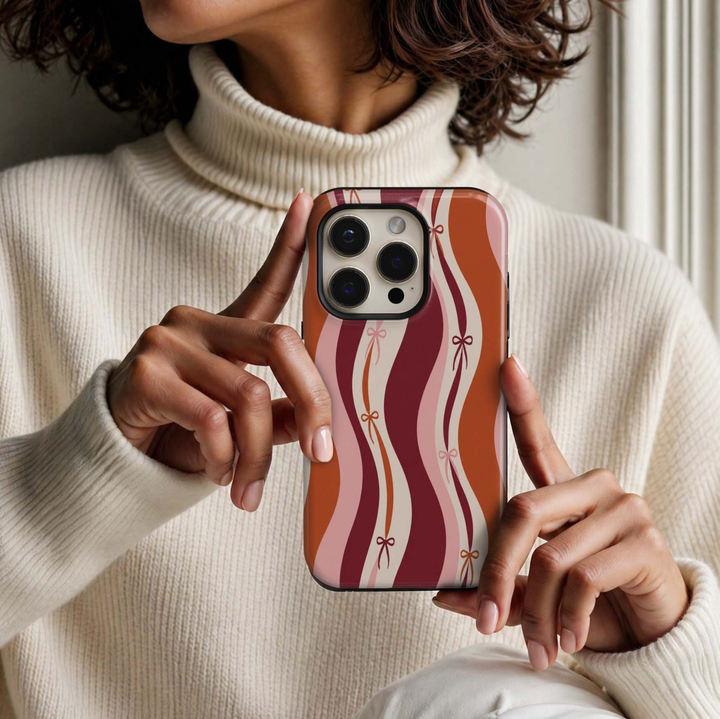 Autumn Coquette Tough iPhone Case featuring wavy burgundy, burnt orange, blush pink and cream stripes with delicate bow accents in a feminine fall design.