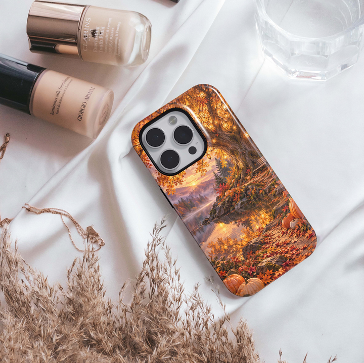 Golden Lakeside Tough iPhone Case featuring a glowing autumn lake, golden fall trees, hanging lanterns, pumpkins, a cozy bench and misty mountains at sunset.