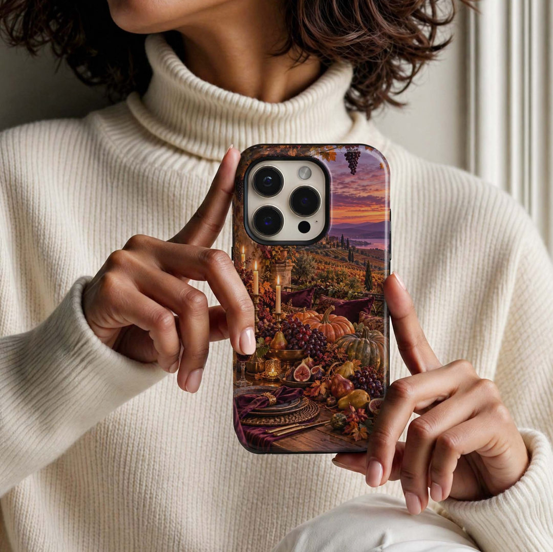 Harvest Table Tough iPhone Case featuring an elegant autumn tablescape with pumpkins, grapes, figs, pears, glowing candles and burgundy accents overlooking a vineyard at sunset.