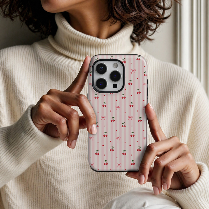 CASELIX Cherry Sweetheart Stripes iPhone 18 Pro Max tough phone case featuring pastel pink and ivory vertical stripes decorated with tiny red cherries, pink ribbon bows, and miniature red hearts. Cute coquette aesthetic phone case for women with a glossy printed finish and romantic cherry pattern.