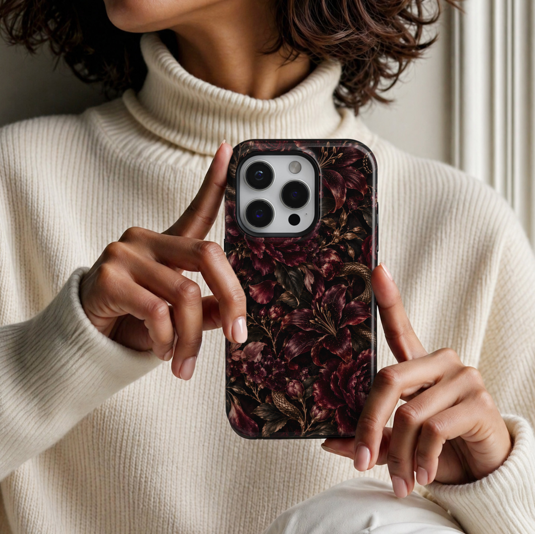 Serpent Bloom iPhone 18 Pro Max tough phone case featuring dramatic burgundy lilies, deep wine-red peonies, delicate floral buds, antique gold serpents weaving through dark botanical foliage, and subtle golden accents against a rich black background with a glossy printed finish.