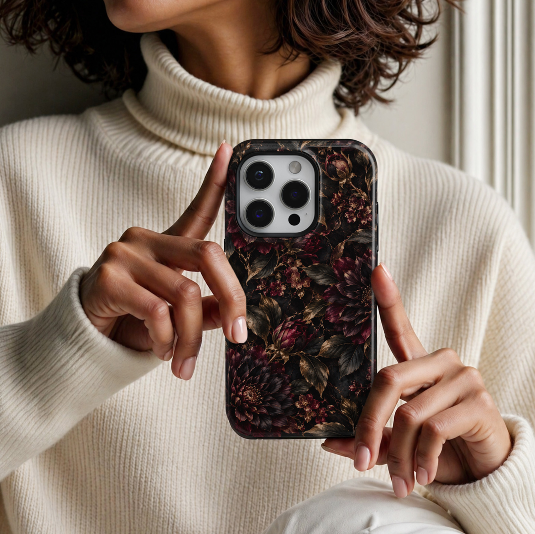 Midnight Bloom iPhone 18 Pro Max tough phone case featuring dramatic deep burgundy and black dahlias, dark wine red rosebuds, antique gold botanical leaves, delicate floral accents and subtle gold veining against a rich black background with a glossy printed finish.