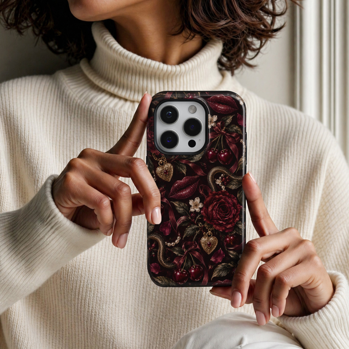 Forbidden Kiss iPhone 18 Pro Max tough phone case featuring deep burgundy roses, glossy cherry red lips, dark red cherries, antique gold snake details, vintage heart lockets, pearl strands and satin ribbons against a dramatic black background with a glossy printed finish.
