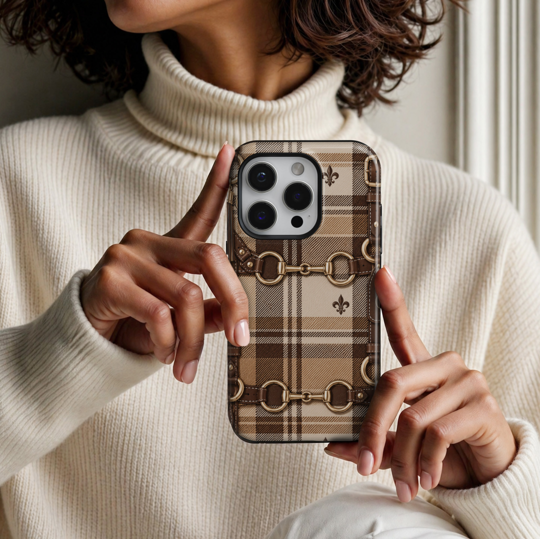 Equestrian Plaid iPhone 18 Pro Max tough case featuring a classic beige, camel and chocolate brown tartan plaid pattern with gold horsebit buckles, brown leather-inspired straps and elegant fleur-de-lis accents in a glossy printed finish.