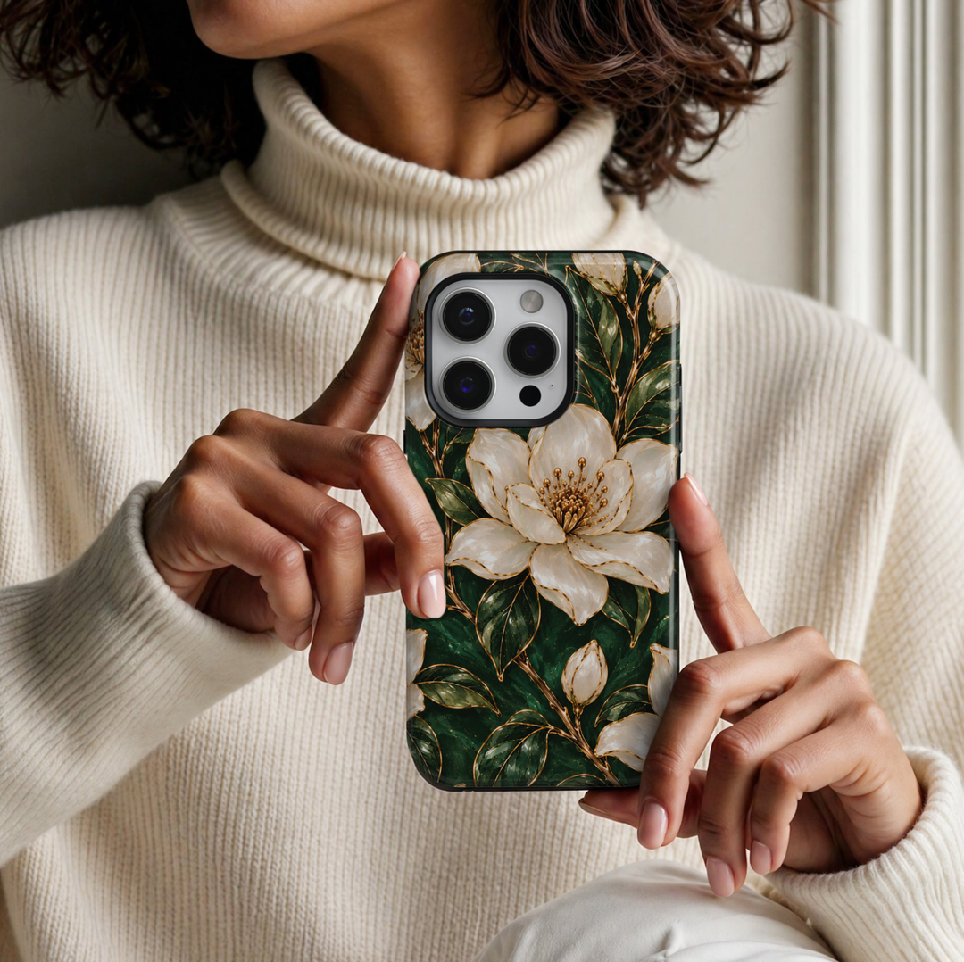 CASELIX Emerald Blossom iPhone 18 Pro Max case featuring elegant ivory white magnolia flowers with intricate gold outlines, golden floral centers, deep emerald green foliage and delicate botanical branches against a rich forest green background with a glossy printed finish.